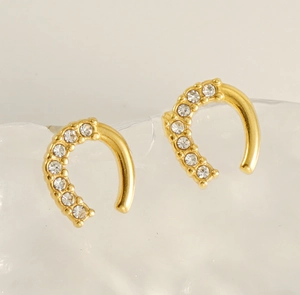 Vue macro de boucles d'oreilles fer à cheval dorées avec pavé de zircons étincelants