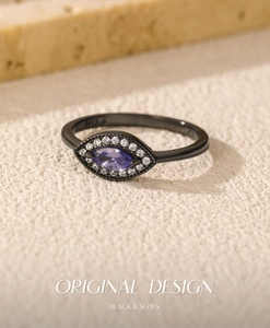 Macro shot of black gold ring with marquise-cut purple stone and white diamond accents