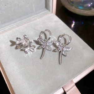 Macro detail of silver dragonfly earrings and ring set with sparkling zircons in a velvet box