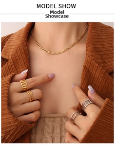 Close-up of interlocking gold necklace and stacked silver and gold rings on a model