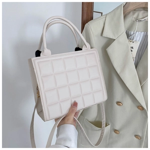 Detailed macro view of quilted texture and round handle on cream white square tote bag