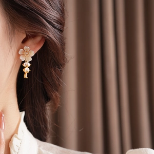 Close-up of elegant gold flower earrings with white petals and sparkling cubic zirconia