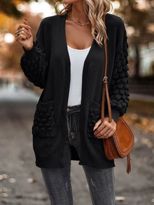 Detail of black knitted cardigan featuring bubble texture sleeves and large pockets