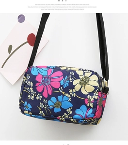 Close-up of adjustable nylon strap and floral pattern on navy blue crossbody bag