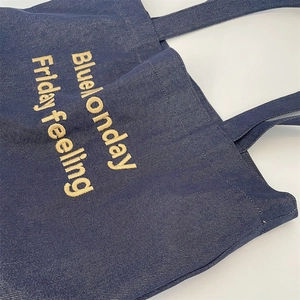 Detailed texture of blue denim tote bag featuring yellow Blue Monday embroidery