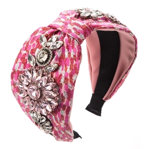 Close-up of pink tweed headband with crystal floral embellishment and fabric texture
