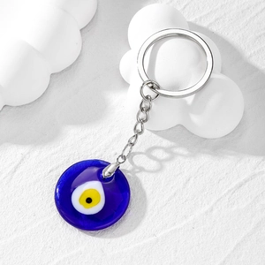 Macro shot of glass Evil Eye charm with circular blue pattern on a white cloud prop
