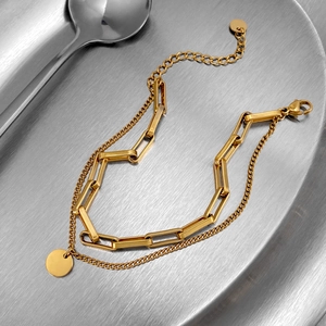 Golden double-layer bracelet with rectangle link chain and round pendant on metal tray
