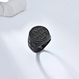 Macro detail of black matte St. Benedict medal ring on a minimalist white stone base