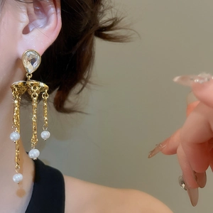 Detail of vintage gold tassel earrings with pearls and crystals worn by a model
