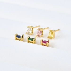 Macro shot of colorful pear-cut zircon earrings set in golden claw settings