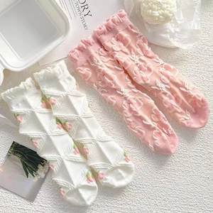 Nahaufnahme von rosa Blumenmuster und weißen Rautenmustern auf weichen Baumwollsocken