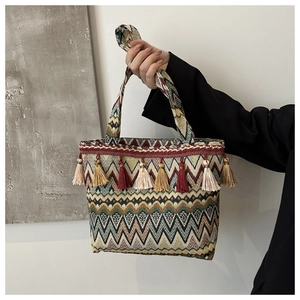 Detail of ethnic woven tote bag with colorful wave patterns and bohemian tassels