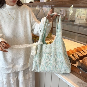 Detail of mint green lace tote bag with white floral embroidery and ribbon bow
