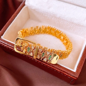 Detail of 18k gold plated geometric buckle bracelet with green and clear gemstones