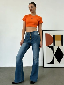 Détail du jean évasé à taille haute avec boutons frontaux et poches cargo en denim