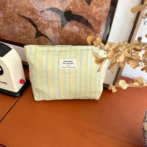 Detailed close-up of yellow and blue striped canvas makeup bag on a wooden table
