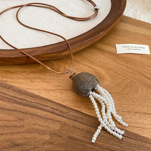Detailed macro of vintage nut shell pendant with elegant white pearl tassels