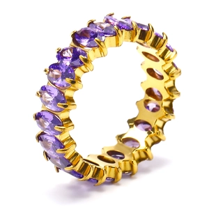 Macro shot of gold eternity ring featuring oval-cut purple zircons in claw settings