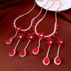 Detailed view of gold and silver floral jewelry sets with red zircon on dark velvet