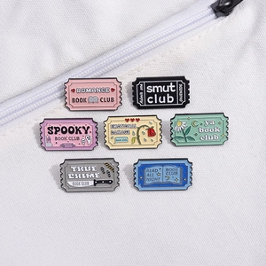 Set of 7 colorful enamel pins featuring vintage book club movie ticket designs on white fabric