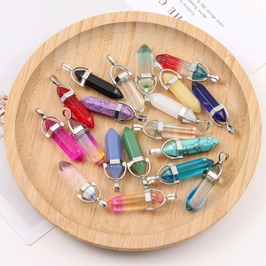 Natural crystal hexagonal pillar pendants in diverse colors on a wooden tray display