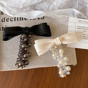 Primo piano di eleganti elastici per capelli con fiocco, perle e perline metalliche.