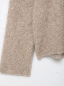 Dettaglio del maglione in maglia di alpaca beige con consistenza morbida e polsini