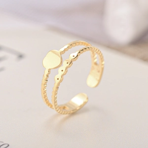 Detail of a double-layered gold open ring featuring a heart charm and beaded band