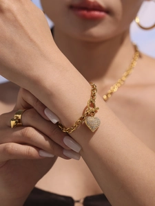 Dettaglio del bracciale dorato con cuore in zirconi indossato da una modella all'aperto