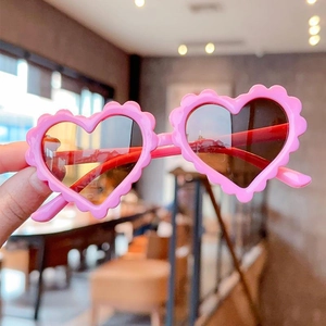 Close-up of pink heart-shaped kids sunglasses with wavy frames and dark lenses
