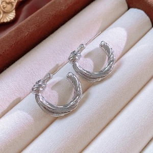 Macro view of silver knotted hoop earrings showcasing metallic texture and polished finish