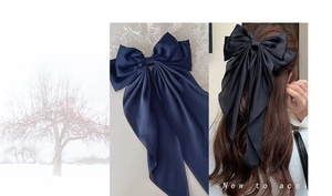 Detail showing elegant dark blue satin bow hair clip with long silk streamers