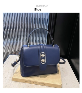 Detailed close-up of a blue PU leather handbag with a gold metal clasp on an art book