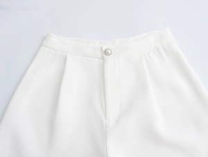 Detail of white wide-leg trousers featuring a pearl button and elegant waist pleats