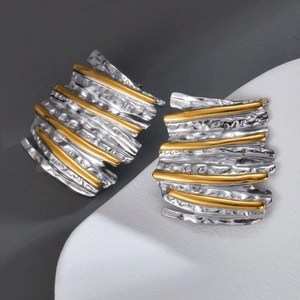 Close-up of stylish wavy metal stud earrings with gold and silver dual-tone plating