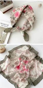 Detail of floral silk scarf showing rose patterns and lace texture in pink and green