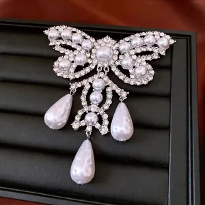 Luxury butterfly brooch with rhinestones, pearls and triple teardrop pendants on black velvet