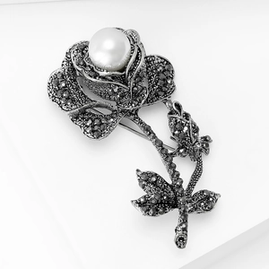 Detailed view of vintage silver rose brooch with black crystals and pearl center