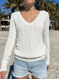 Detailed macro view of white V-neck cable knit sweater with ribbed cuffs and hem textures