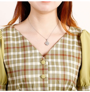 Primo piano di una collana con ciondolo a quadrifoglio in argento su una modella