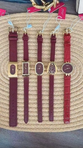 Detailed collection of elegant gold ladies watches with dark red leather straps on a mat