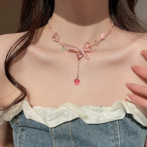 Close-up of pink beaded choker with resin heart pendant and ribbon bow on model neck