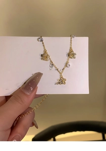 Close-up of a gold flower anklet with sparkling zircon crystals held in a hand
