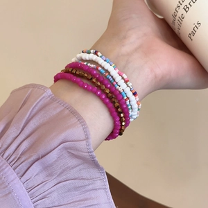 Detail of five-layer Bohemian colorful bead bracelets worn on a wrist in warm lighting