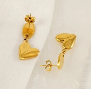 Detailed macro view of gold-plated heart earrings with LOVE engraving and polished finish
