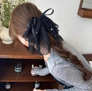 Elegant black pleated mesh bow hair clip with pearls shown on model's hairstyle