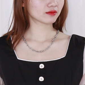 Macro view of silver stainless steel infinity link chain necklace worn on model's neck