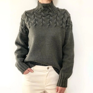 Detail of dark green chunky knit turtleneck sweater with vintage cable stitch patterns