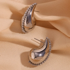 Vue macro de boucles d'oreilles gouttes argentées avec zircons sur fond de soie